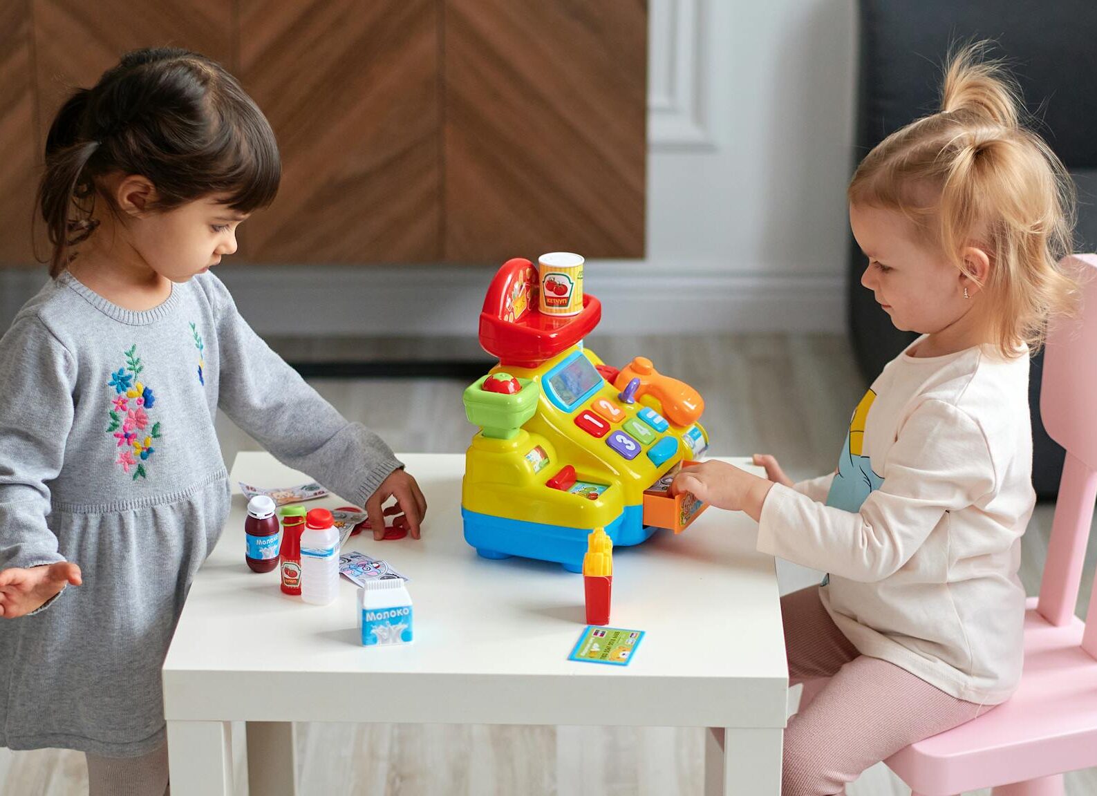 Where to Go... by Entry Cost Two young girls engaged in imaginative play with a toy cash register at home.